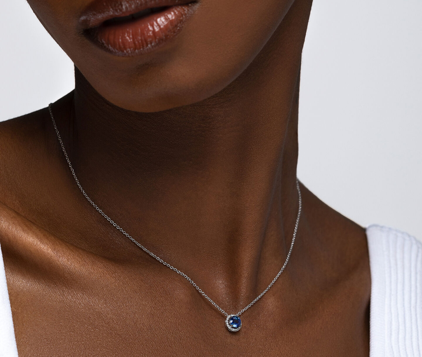 A woman wearing a Birks Ros&eacute;e du Matin sapphire and diamont pendant.