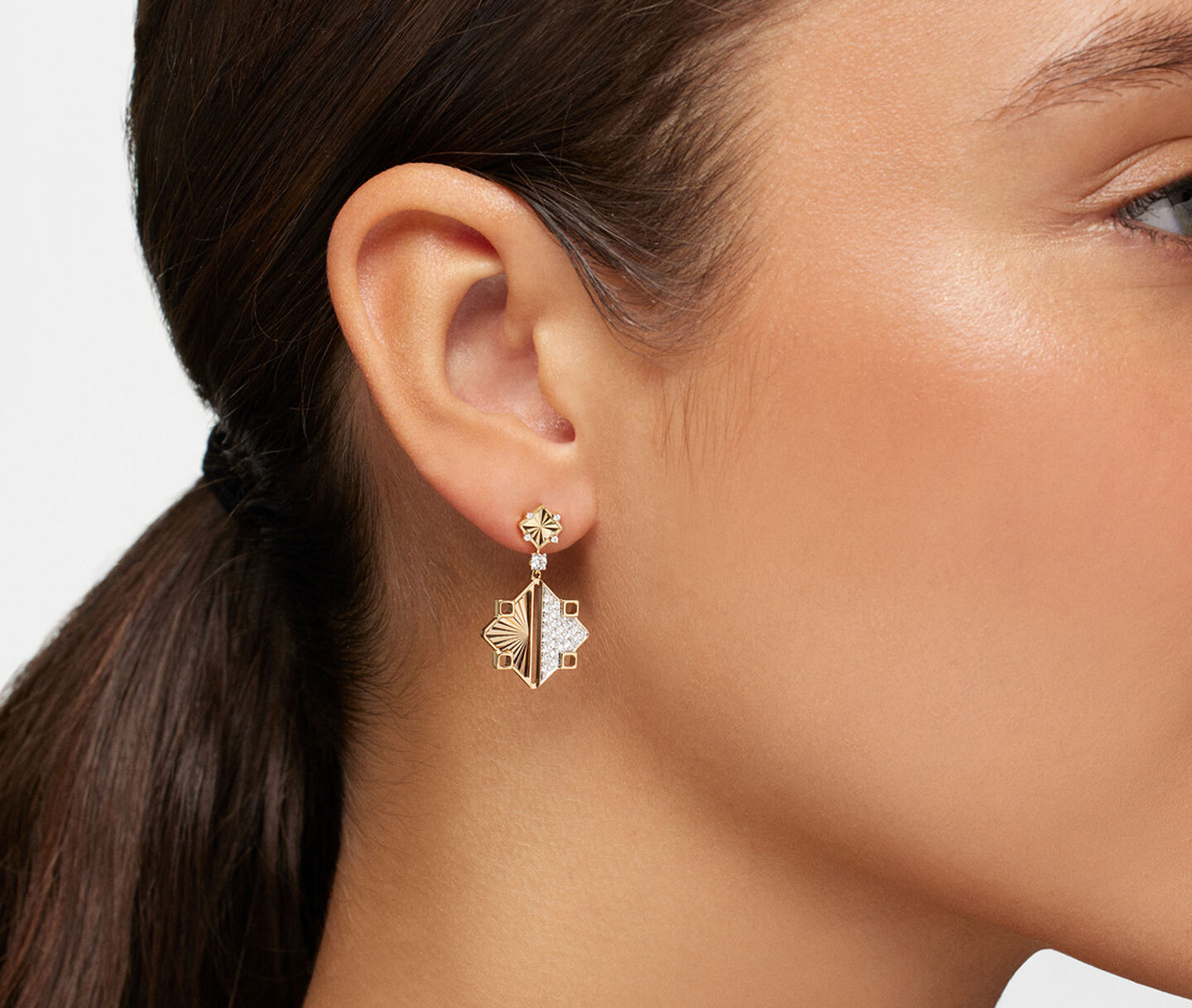A woman wearing a Birks Muse gold and diamond drop earrings.