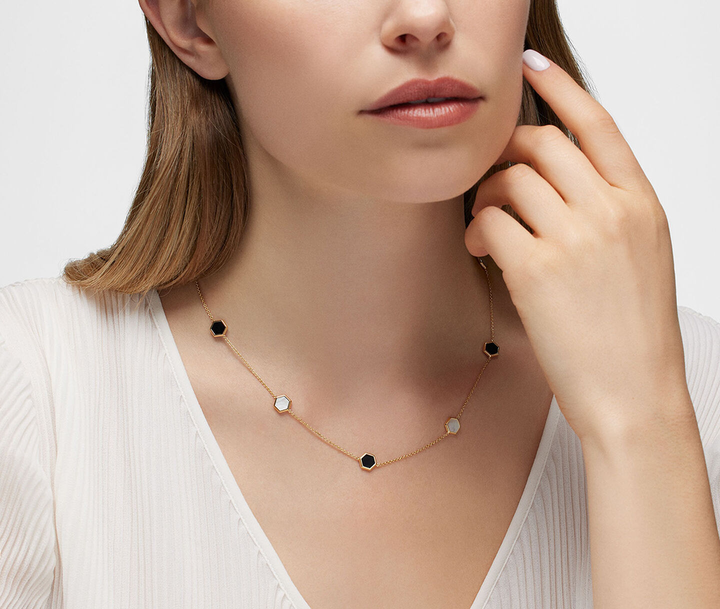 A woman wearing a Birks Bee Chic onyx and mother-of-pearl station necklace.