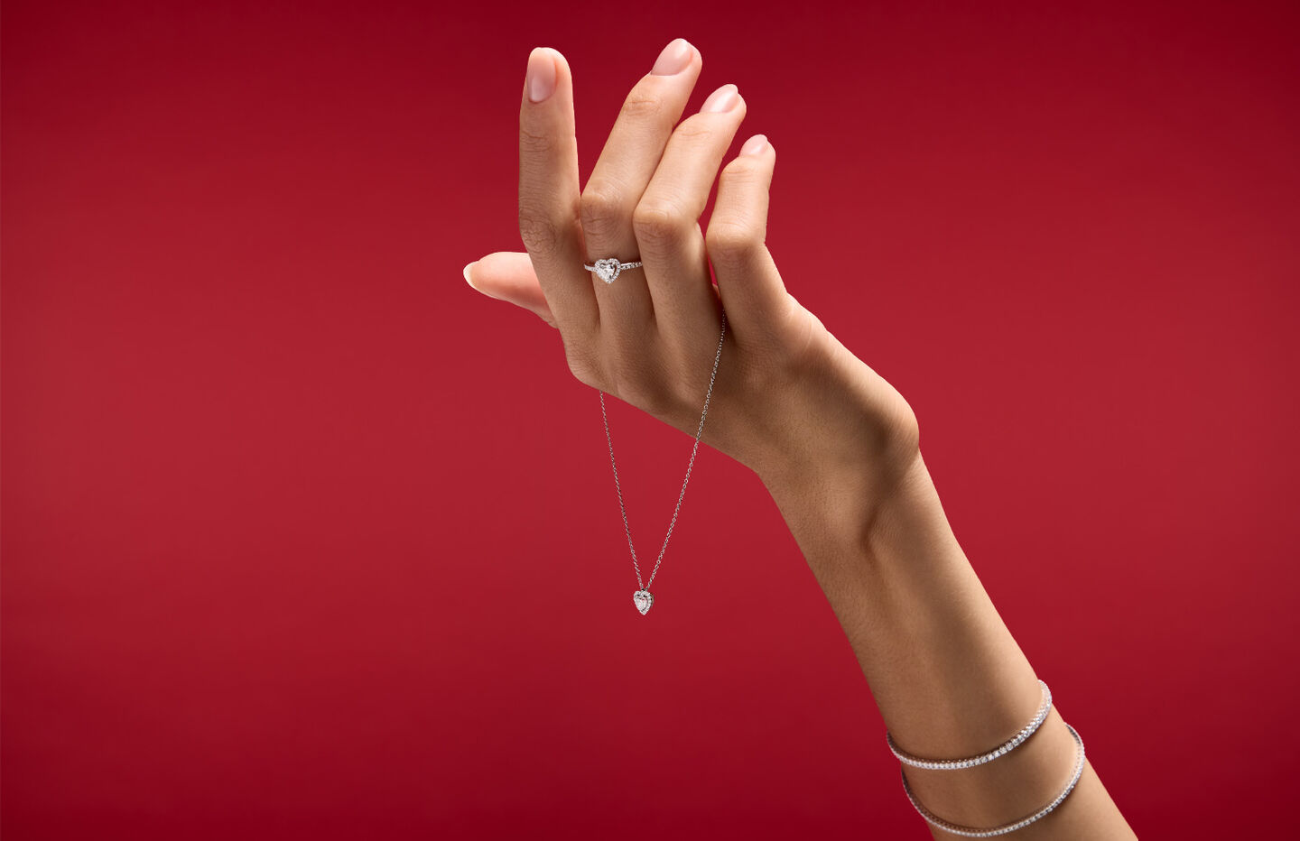 A woman holding Maison Birks jewellery on red background.