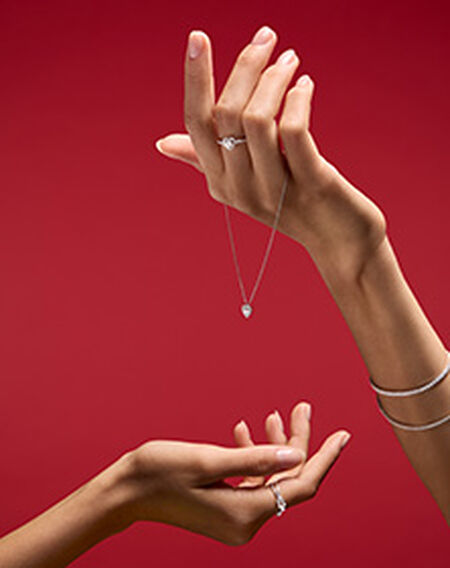 Birks Essentials heart jewellery on a red background.