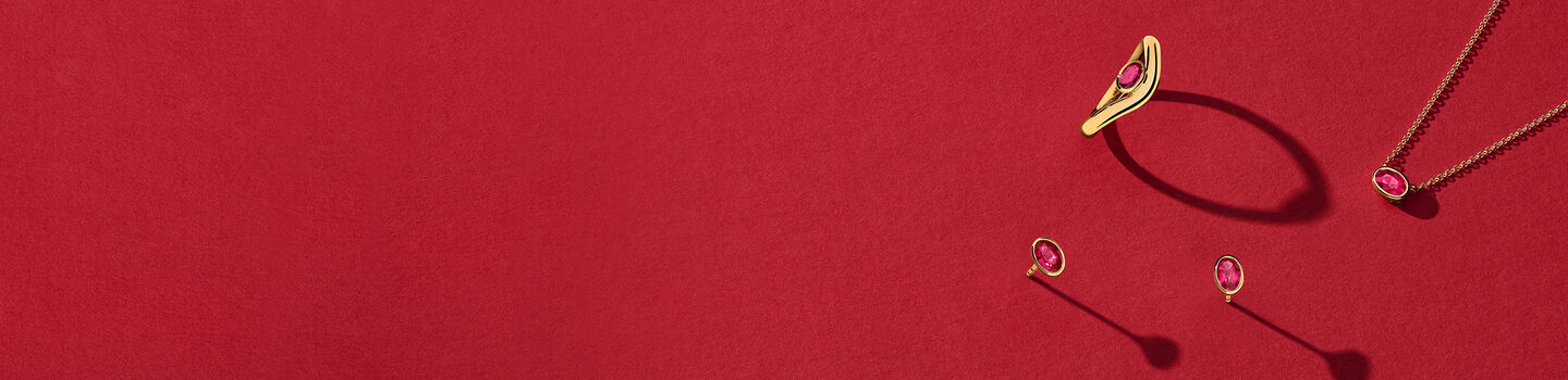 Birks Essentials ruby and yellow gold jewellery on a red background,