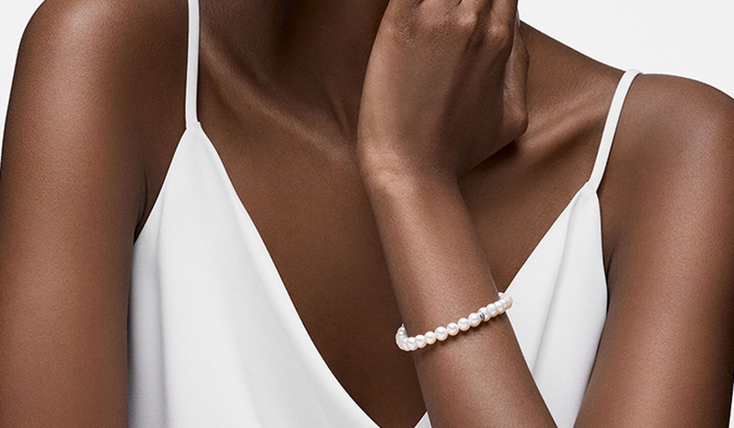 A woman wearing a Birks freshwater pearl elastic bracelet.