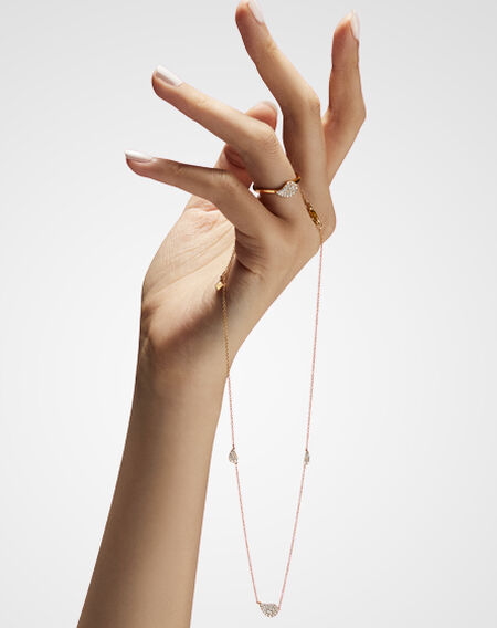 A woman's hand wearing a Birks P&eacute;tale yellow gold and diamond ring and yellow gold and diamond station necklace