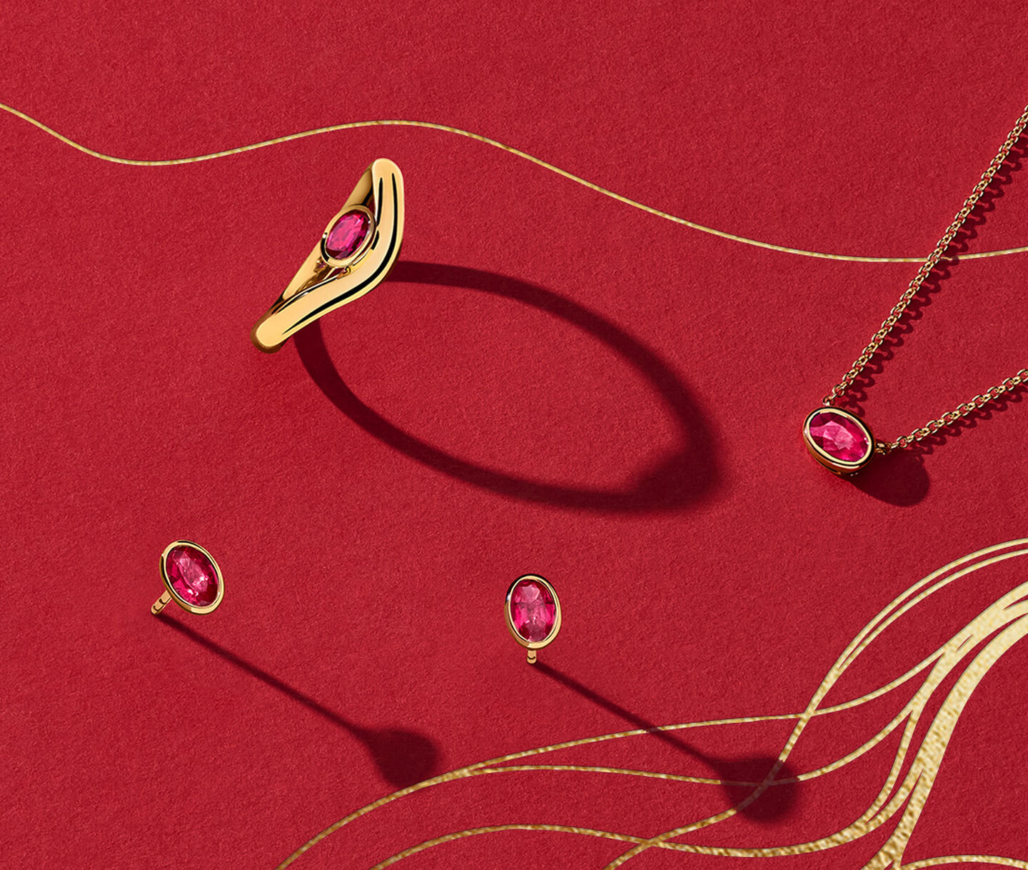 Birks Essentials yellow gold and ruby jewellery on a red background.