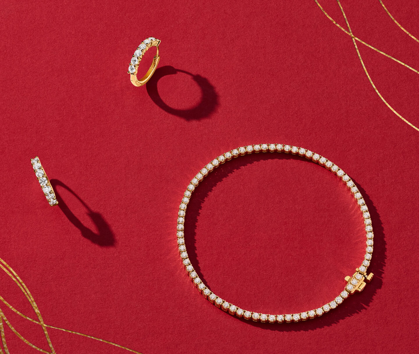 Birks diamond and yellow gold bracelet and earrings on a red background.