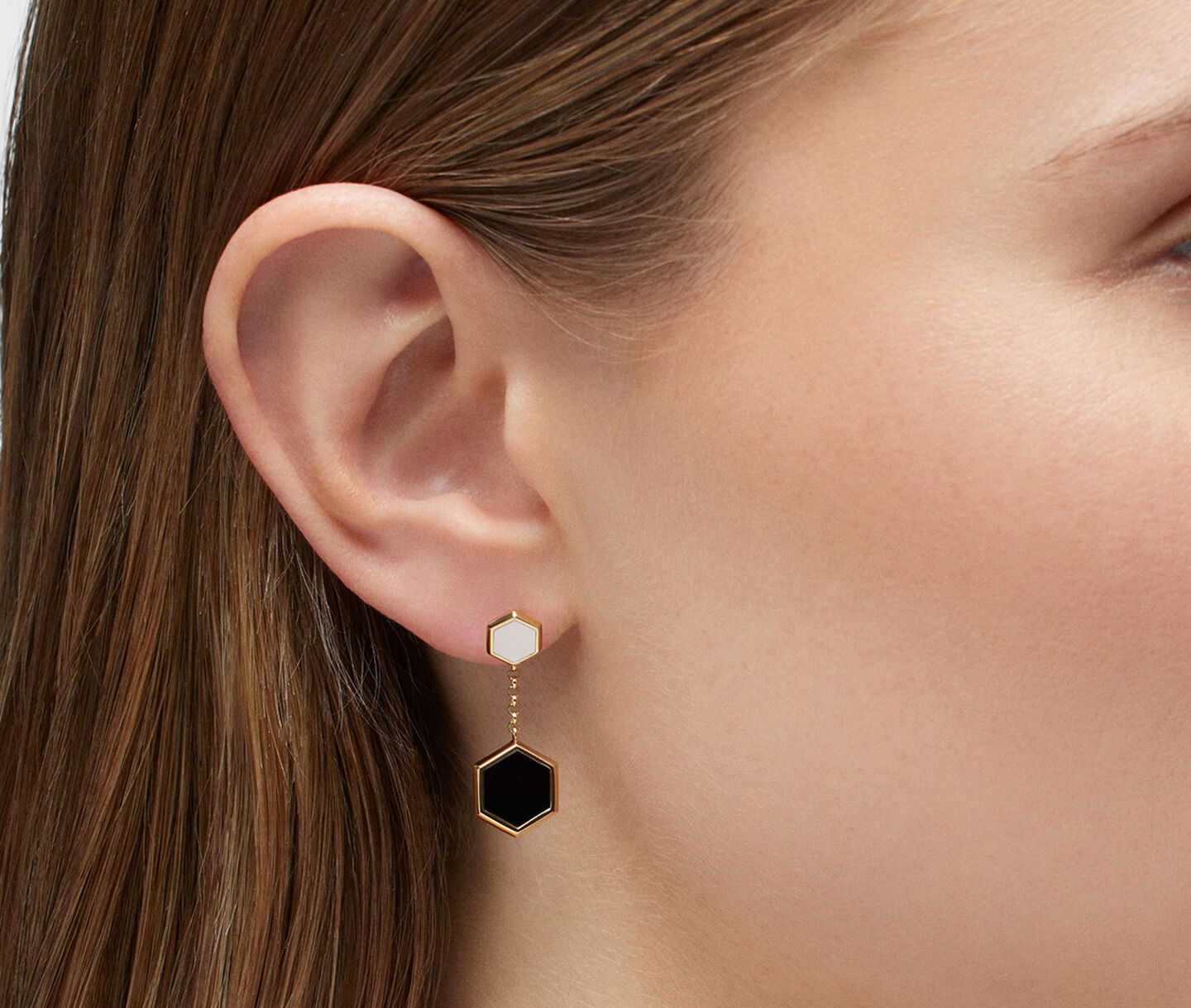 A woman wearing Birks Bee Chic onyx and mother-of-pearl earrings.