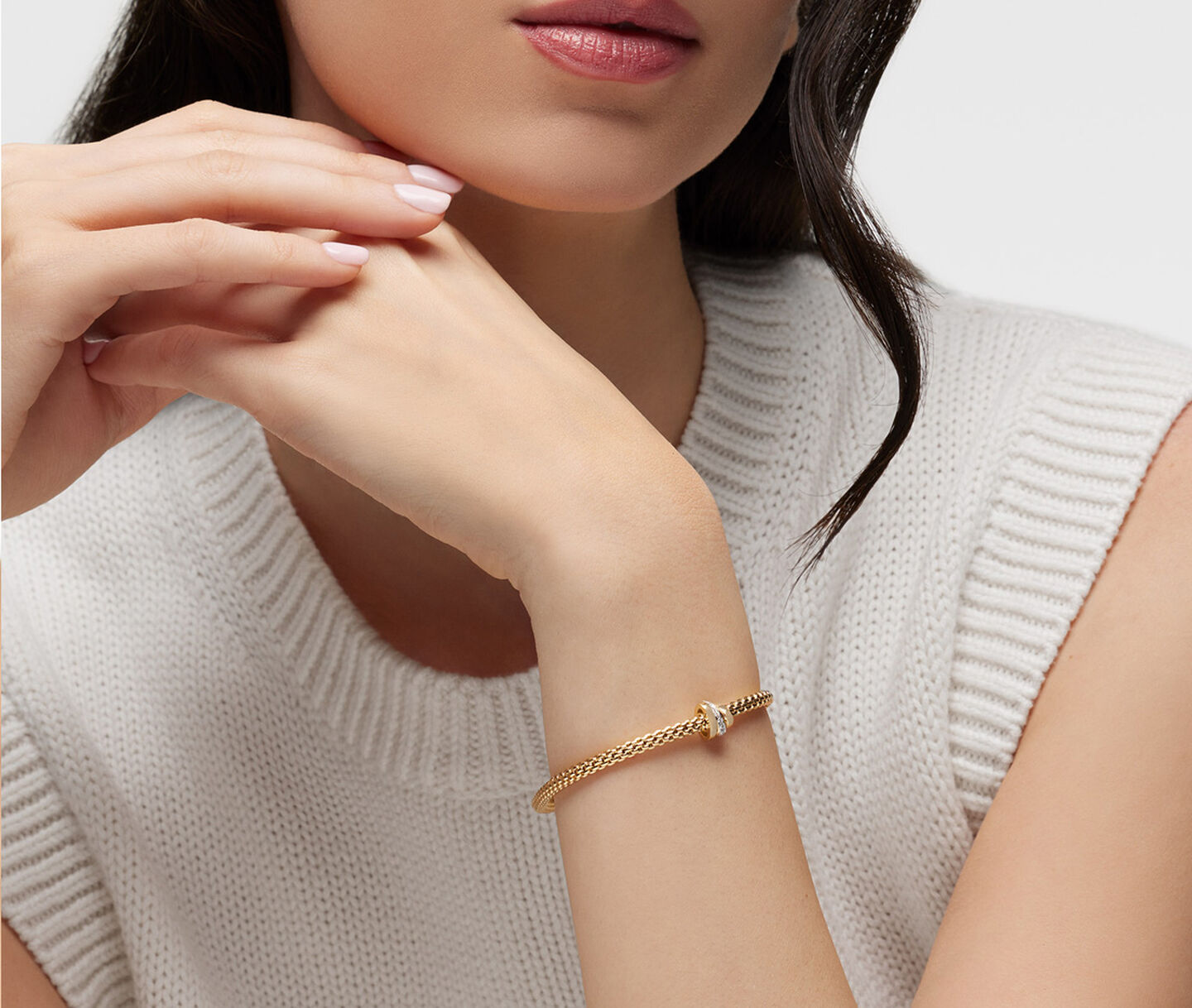 A woman wearing a FOPE yellow gold and diamond bracelet.