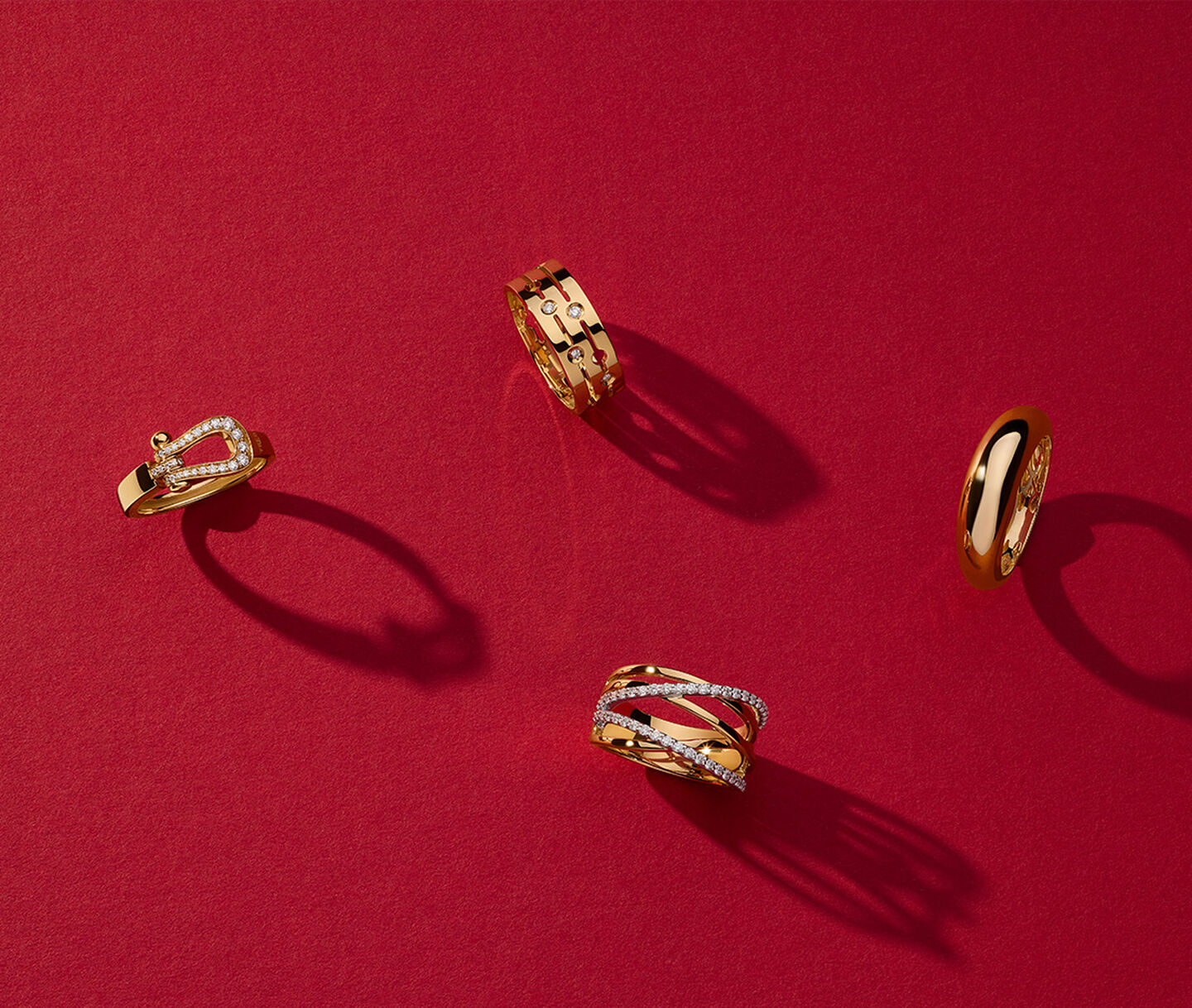 Four gold rings from Maison Birks on a red background.