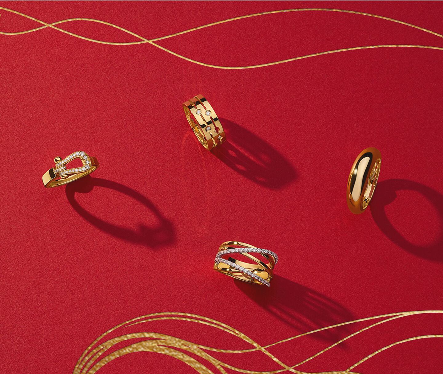 Four gold rings from Maison Birks on a red background.