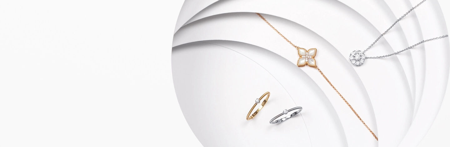 Two Marco Bicego Bi49 white and yellow gold rings next to two Roberto Coin Princess Flower pendants and a round Birks Snowflake diamond pendant