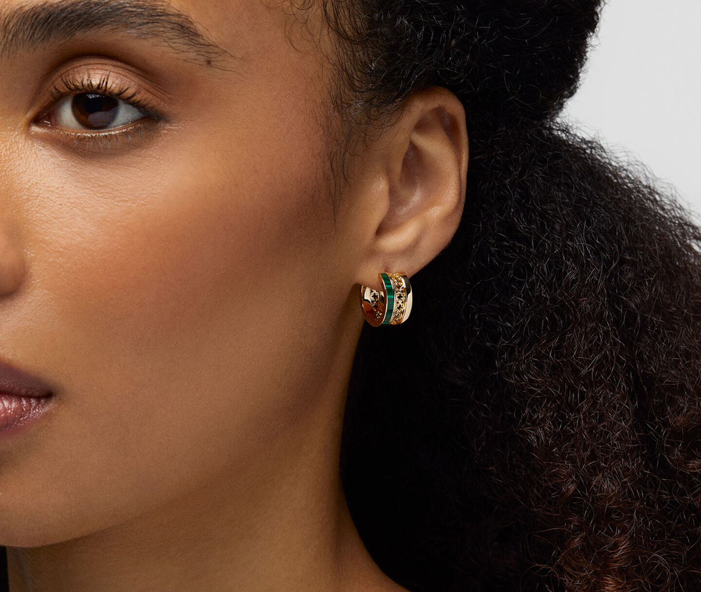 A woman wearing Birks Dare to Dream malachite huggie earrings.