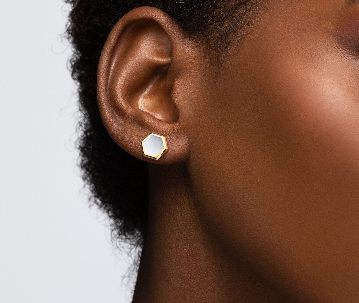 A woman wearing Birks Bee Chic yellow gold and mother-of-pearl earrings.