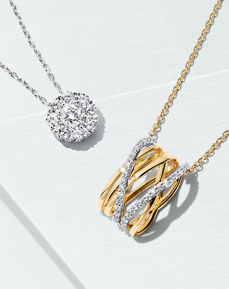 A Birks Snowflake round pav&eacute; diamond pendant and a Birks Ros&eacute;e du Matin pendant with yellow gold and diamonds on a blueish background.