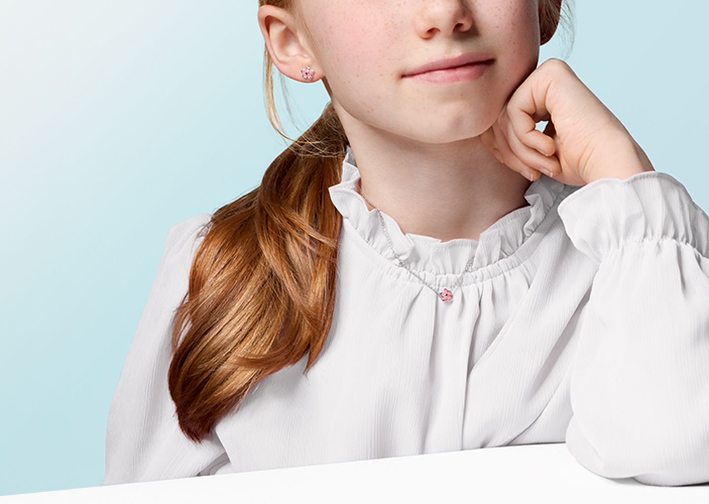 A child wearing a Birks necklace and earrings.