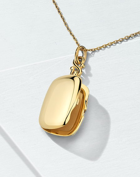 Monica Rich Kosan yellow gold locket on a light blue background.