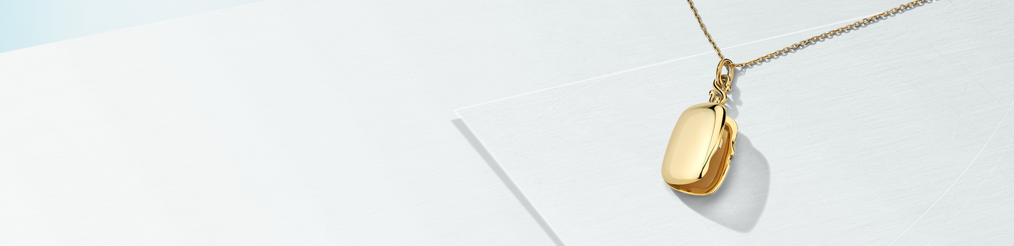 A Monica Rich Kosann yellow gold locket on a white background.