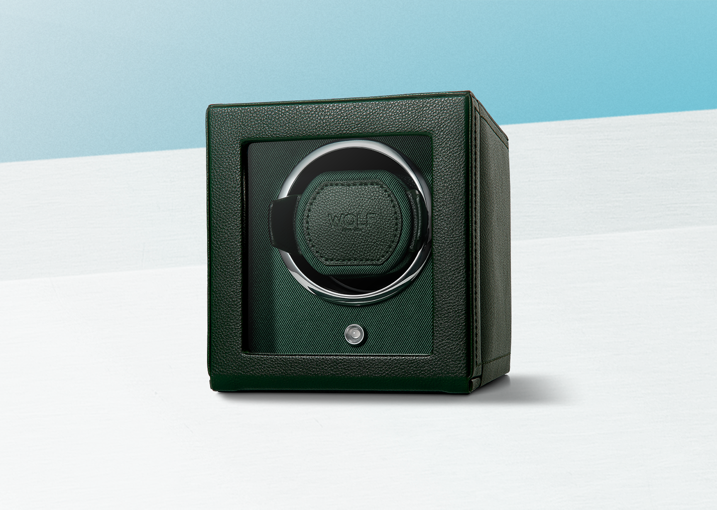 A leather WOLF watch winder on a light blue background.